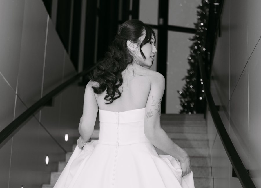 A bride looking back over her shoulder on a staircase, in black and white
